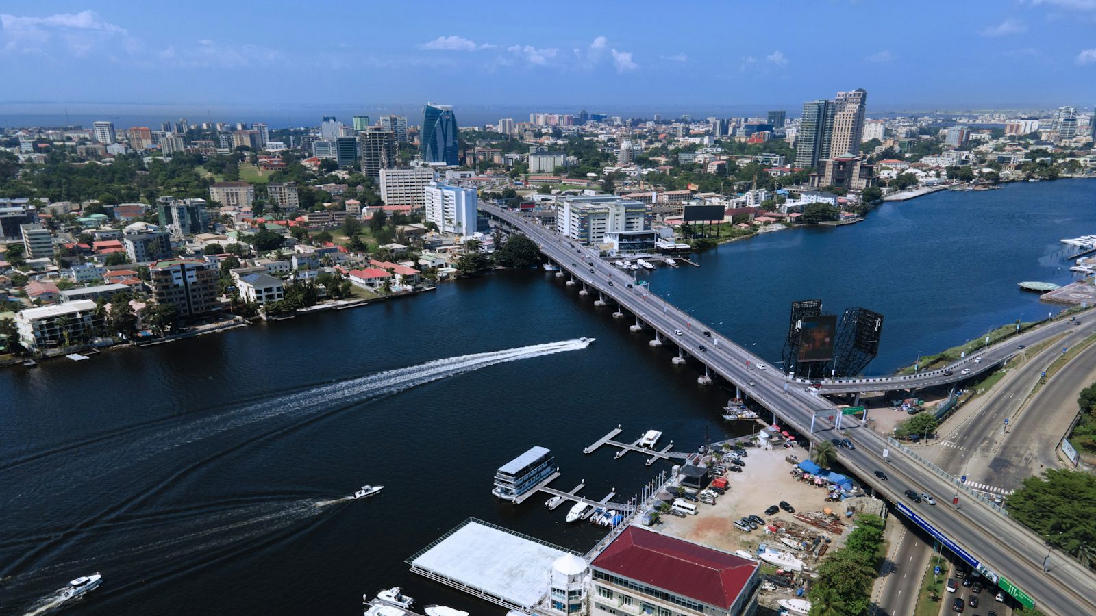 Aerial view of Victoria Island, Lagos, with boats crossing the lagoon and the business district skyline beyond